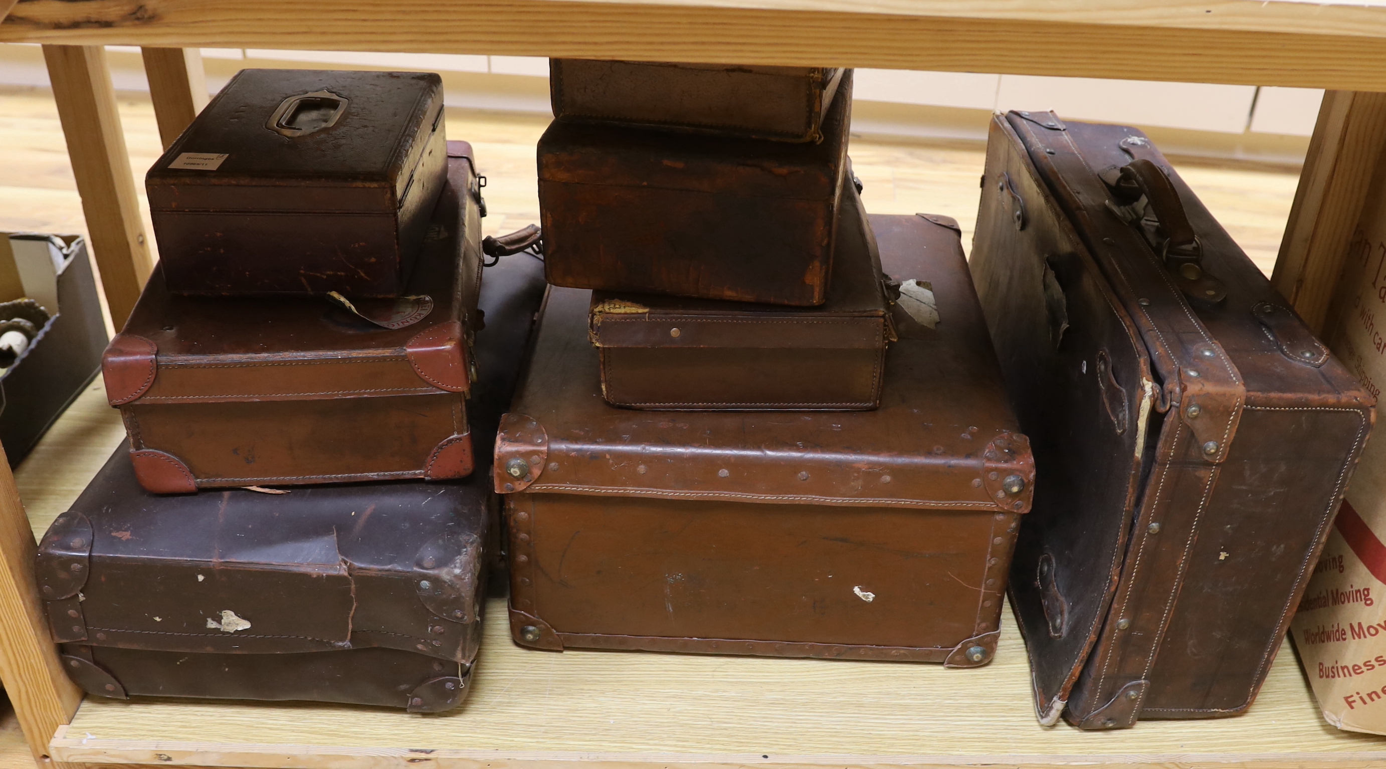 Seven vintage leather suitcases and a leather writing box (locked), the largest 60cm wide